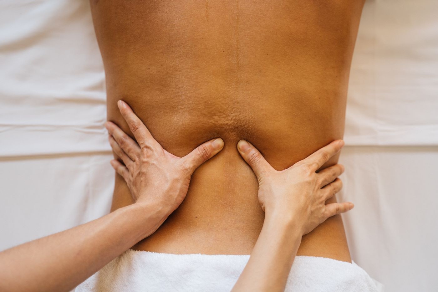 Massage du dos aux mains d'une praticienne, lumière claire